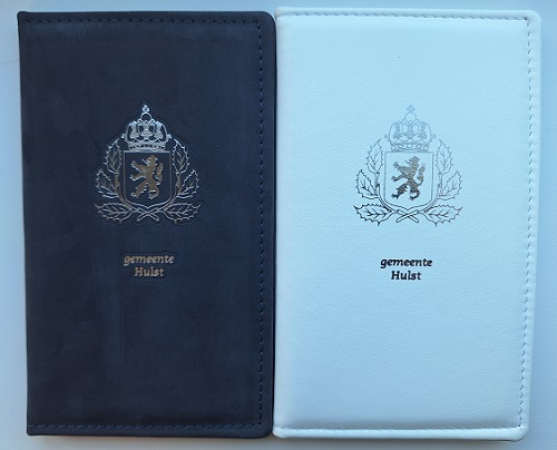 Foto trouwboekjes, links het blauwe trouwboekje, rechts het witte trouwboekje. Op beide boekjes staat in zilverkleur het gemeentewapen van gemeente Hulst.